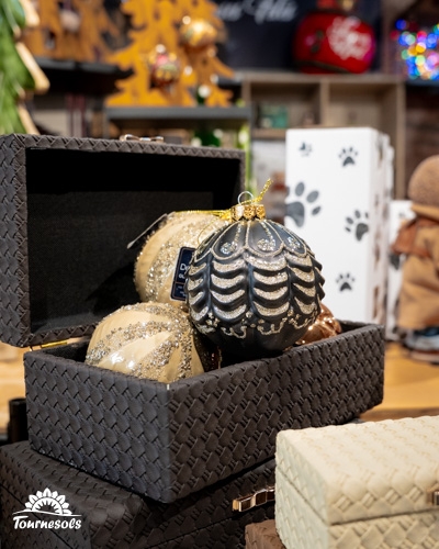 Boules de Noël dans une boîte tressée, décor rustique en arrière-plan.